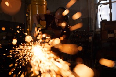 Atölyede duran ve kesme makinesi ile metal testere kulak koruyucuları meşgul fabrika işçisi