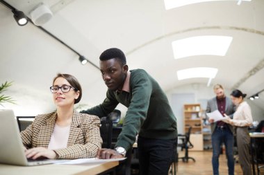 Ofiste çalışırken kadın meslektaşı ile dizüstü bilgisayar kullanan genç Afrikalı işadamıportresi, kopya alanı