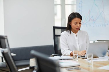 Ofiste çalışırken dizüstü bilgisayar kullanarak karışık ırk iş kadını Portresi, kopya alanı