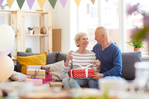 Positive Excited Beautiful Senior Couple Casual Outfits Sitting Sofa Opening — Stock Photo, Image