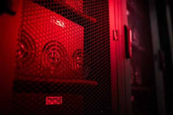 Modern powerful server equipped with video cards in ventilation cabinets at mining farm, red light