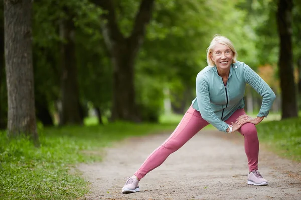 Mature Cheerful Blonde Female Activewear Stretching Legs While Doing Physical — Stock Photo, Image