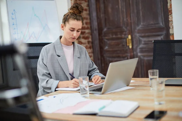 Portrait of female business owner working in office sitting at table in conference room, copy space