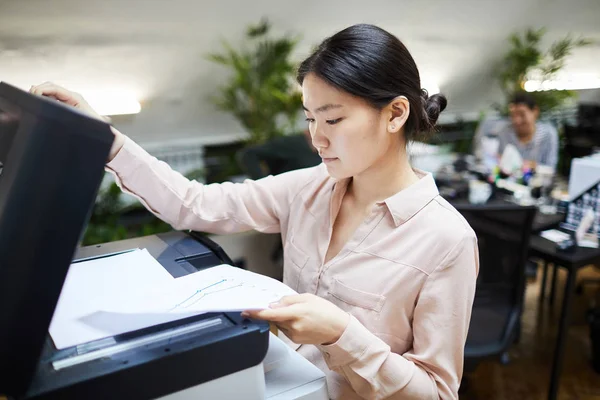 Portrait of Asian businesswoman scanning documents while working in office, copy space