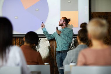 Konferans salonunda projektör ekranında sunum yapan çağdaş sakallı adamın portresi, kopya alanı