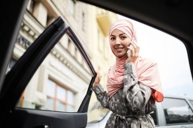 Hijab araba kapısını açma ve camer bakarak Neşeli güzel genç kadın