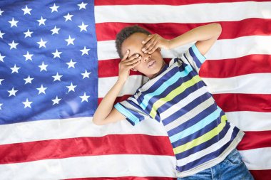 Amerikan bayrağı ekose yatan ve elleriyle gözleri kaplayan soyulmuş tshirt Ciddi Siyah çocuk