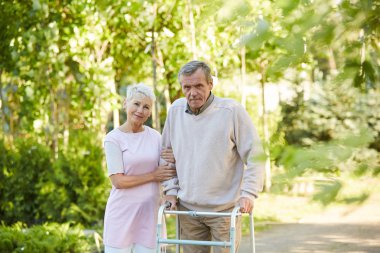Güneşli parkta eşi ile poz walker eğilerek kıdemli adam Portresi, kopya alanı