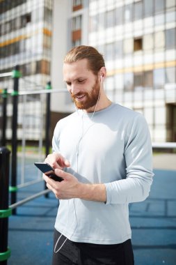 Eğitim alanında duran ve koç ile online iletişim için akıllı telefon kullanarak kazak Mutlu yakışıklı sakallı adam