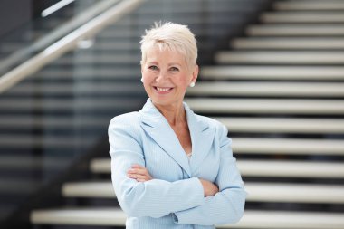 Lobide çapraz kolları ile ayakta mavi ceketneşeli çekici iş kadını Portresi