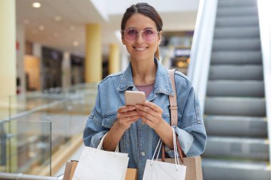 Alışveriş hakkında yeni blog yazıları yazarken alışveriş merkezinin ortasında duran genç gülümseyen stilist