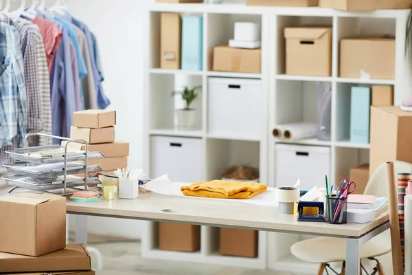 Malzemeleri ile çağdaş online mağaza yöneticisi Masası, katlanmış pullover ve paketlenmiş kutu yığını