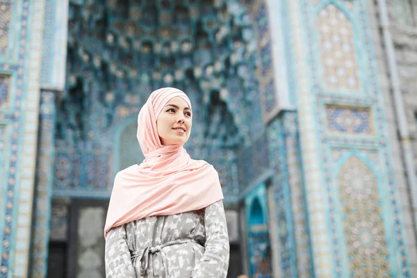 内容有吸引力的年轻穆斯林妇女在头巾站在五颜六色的清真寺与装饰品和望去 — 图库照片