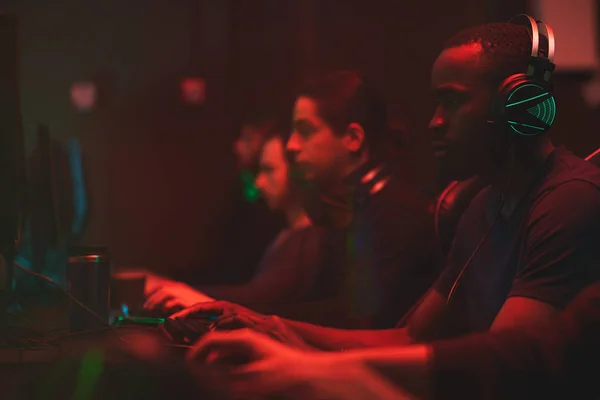 Группа Концентрированных Мультиэтнических Игроков Сидящих Перед Компьютерами Темной Комнате Полной — стоковое фото
