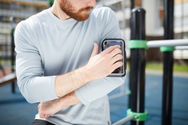 Spor zemin üzerinde duran ve omuz da durumda akıllı telefon sabitleme kazak ciddi kırmızı sakallı adam yakın çekim