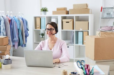 Genç gülümseyen yardım masası yöneticisi siparişlerini alırken müşterilerle çevrimiçi konuşuyor