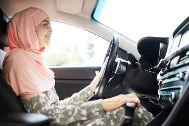 Hijab direksiyon simidi pozitif kendinden emin genç Müslüman kadın sürücü ve araba sürerken vites değiştirme