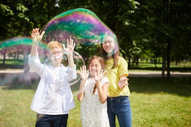 Yaz parkında eğlenirken birlikte büyük sabun kabarcıkları ile oynarken rahat kıyafetler içinde jolly heyecanlı çok ırklı çocuklar