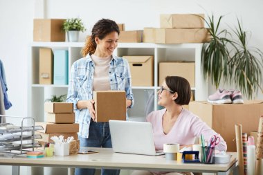 Online mağaza ofisinin iki genç yöneticisi müşteriler için sipariş hazırlarken masa başı etkileşimde