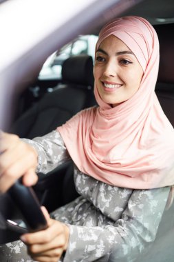 Pembe hijab mutlu kendinden emin genç Arap kadın direksiyon başında oturan ve araba sürüş