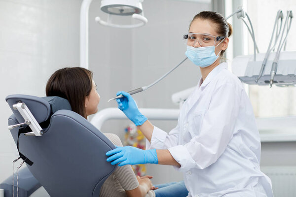 Portrait of smiling female dentist looking at camera while working with child patient, copy space