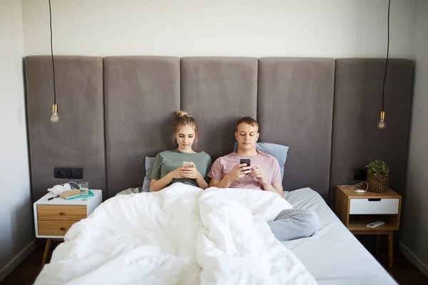 Genç Mobil Çift Uykudan Sonra Akıllı Telefonlarını Kullanırken Yatakta Yatıyor — Stok fotoğraf