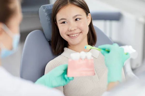 Retrato Sorridente Menina Asiática Sentado Cadeira Dentária Ouvir Dentista Segurando — Fotografia de Stock