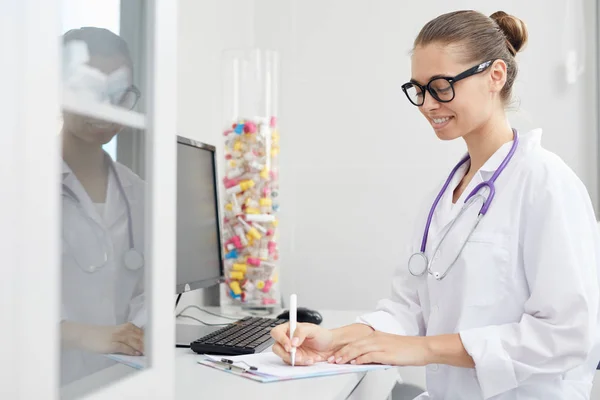 Side View Portrait Smiling Female Doctor Writing Clipboard While Sitting — Stock Photo, Image