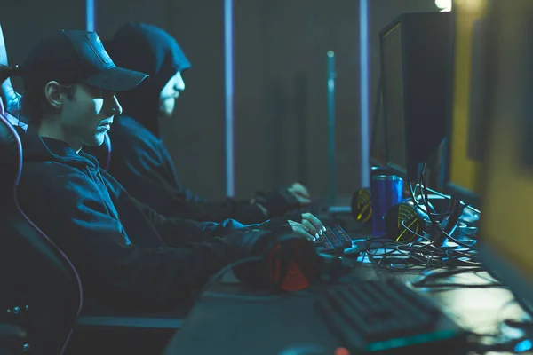 Groep Van Geconcentreerde Hackers Zwarte Hoodies Zittend Rij Aan Tafel — Stockfoto