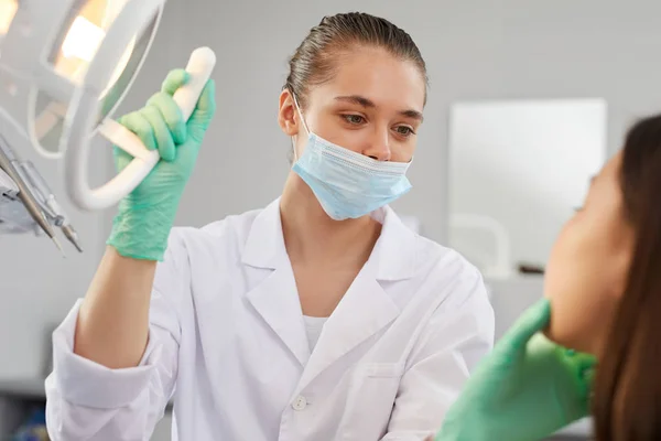 Retrato Una Joven Dentista Ajustando Lámpara Mientras Examina Paciente Clínica — Foto de Stock