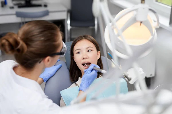 Portret Wysokiego Kąta Żeńskiego Dentysty Wykonującego Zabieg Medyczny Azjatyckiej Dziewczynie — Zdjęcie stockowe