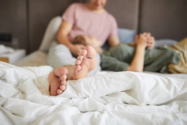 ベッドの上で彼の妻やガールフレンドとの休憩中に白い毛布に若いリラックスした男のつま先 — ストック写真