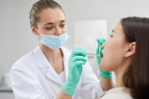 Retrato Jovem Dentista Usando Máscara Protetora Enquanto Examina Paciente Clínica — Fotografia de Stock