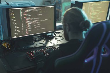 Programlama şirketinde çalışırken masada oturan ve uygulama komut dosyası oluşturan konsantre yazılım mühendisinin arka görünümü