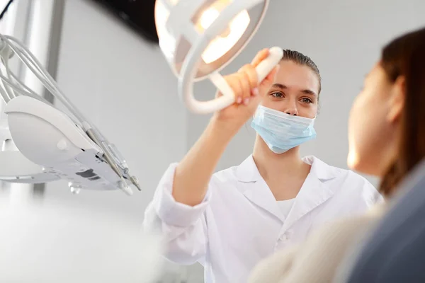 Retrato Baixo Ângulo Jovem Dentista Feminino Ajustando Lâmpada Enquanto Examina — Fotografia de Stock