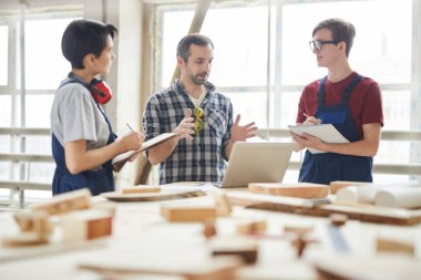 Ahşap atölyesinde projeyi tartışan çağdaş marangozlar grubu, fotokopi alanı