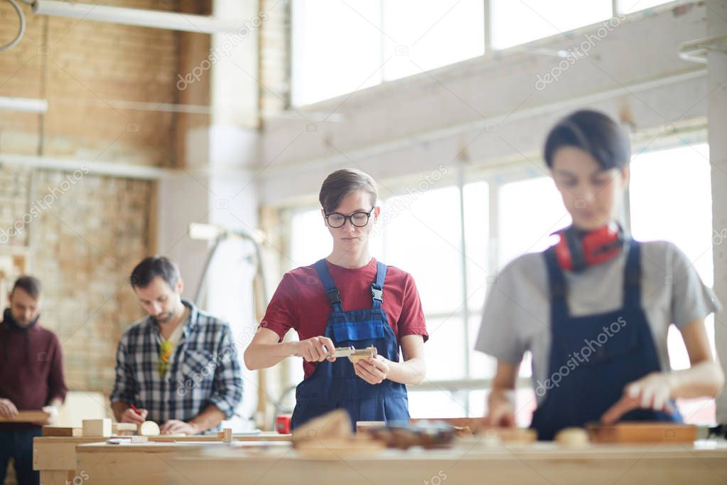 Portrait of modern carpenters working with wood standing in row in workshop, copy space