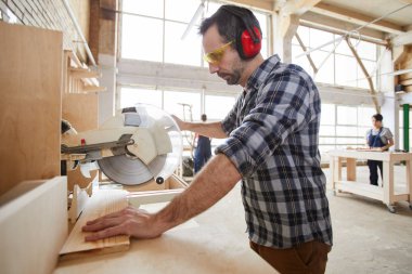 Endüstriyel atölyede ahşap testere olgun marangoz yan görünüm portresi, kopya alanı