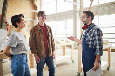Atölyede gençlere konuşan olgun marangoz portresi onlara üretim turu, kopyalama alanı vererek