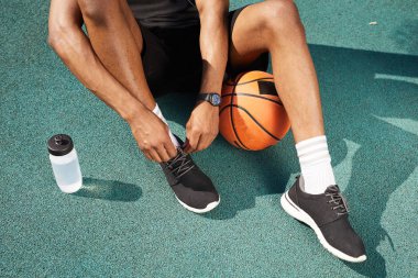 Basketbol sahası açık havada spor ayakkabı bağlama çağdaş Afrikalı-Amerikalı adam Düşük bölüm portre, uzay arka plan kopyalamak