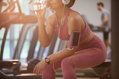 Kol tutucu akıllı telefon odaklanmak spor salonunda genç sporcu içme suyu orta bölüm portre, kopya alanı