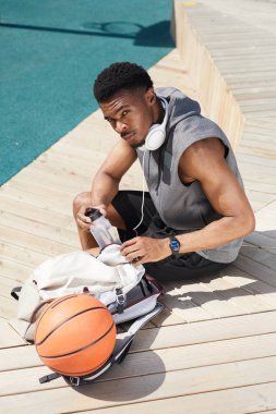 Açık basketbol sahasında dinlenirken kameraya bakan yakışıklı Afrikalı-Amerikalı adamın yüksek açılı portresi, kopya alanı