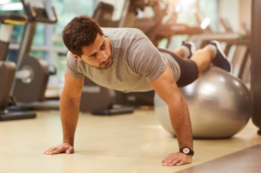Yakışıklı kaslı adam portresi spor salonunda egzersiz sırasında fitness topu üzerinde push up yapıyor, kopya alanı