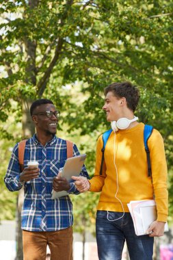 Okula yürürken neşeyle sohbet eden iki üniversite öğrencisinin bel kadar portresi, kopya alanı