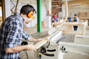 Doğrama atölyesinde odun kesen olgun marangozun arka görüş portresi, kopyalama alanı