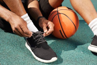 Basketbol sahası açık havada spor ayakkabı bağlama Afrikalı-Amerikalı adam Closeup, uzay arka plan kopyalamak