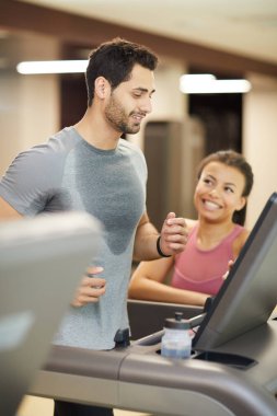 Spor salonunda koşu bandıüzerinde çalışan ve mutlu egzersiz zevk gülümseyen yakışıklı genç adam Portresi