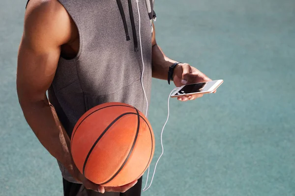 Средняя Секция Неузнаваемого Афроамериканца Держащего Баскетбол Использующего Смартфон Открытом Воздухе — стоковое фото