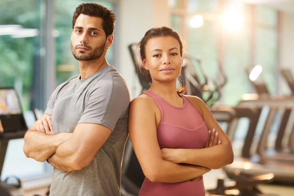 腰起美丽的混合种族夫妇的肖像自信地在健身房站在双臂交叉 复制空间 — 图库照片