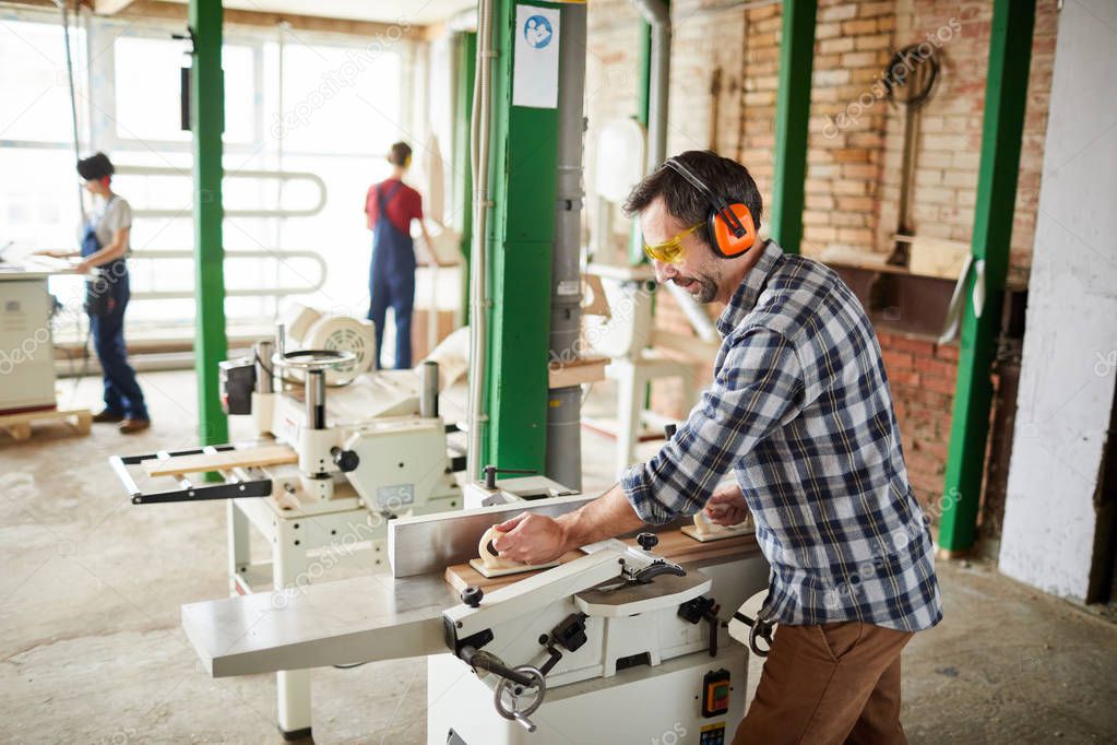 Wide angle portrait of carpenters using machines in joinery workshop, copy space
